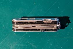 Boczny widok metalowego scyzoryka z suwakowym modułem USB i napisem „32GB” na zielonym tle