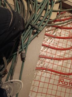 Red underfloor heating pipes attached to mesh-patterned foil