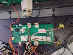 Płytka układu elektronicznego z różnymi podłączonymi przewodami, w tym przewodem w różowej izolacji.
