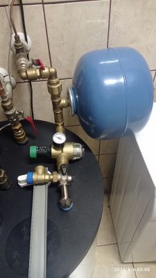 Nowo zainstalowany niebieski zbiornik ciśnieniowy w systemie CWU z zaworem bezpieczeństwa i manometrem.
