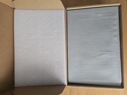 Open cardboard box with two gray items wrapped in protective foam
