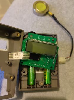 Otwarta obudowa modułu elektronicznego z płytką PCB i bateriami.