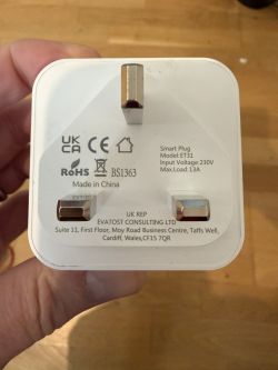 Back of a white UK smart plug with three pins and printed compliance labels