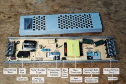 Open switch-mode power supply with labeled PCB components and removed cover