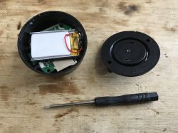 Opened electronic device with exposed battery and small screwdriver on wooden surface