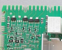 Zbliżenie na płytkę drukowaną ze zmywarki z widocznymi triakami i elementami elektronicznymi.