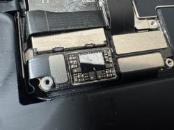 Zbliżenie na uszkodzony układ elektroniczny przy gnieździe baterii w iPhone 13 Pro.