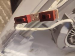 Zbliżenie na przełącznik okapu kuchennego z widocznymi oznaczeniami elektrycznymi.