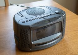 Black portable radio with cassette player on a wooden table