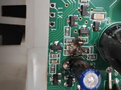 Spalony fragment płytki drukowanej z widocznymi uszkodzonymi elementami elektronicznymi