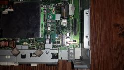 Wnętrze urządzenia z płytką PCB; strzałka wskazuje mały element SMD obok kondensatorów