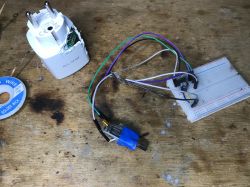 Disassembled Blow Socket with Wiring and Breadboard View of a disassembled Blow electric socket with wiring and a breadboard on a wooden table.