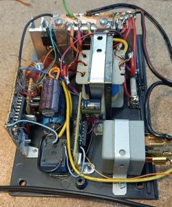 Wnętrze obudowy z elektroniką: transformator, kondensatory i kolorowe przewody na płycie