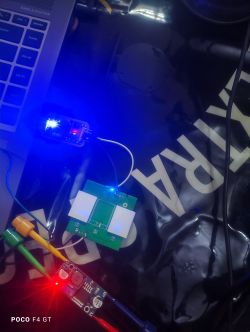 A PCB connected to a laptop and external power supply, with visible wires and illuminated LED indicators.