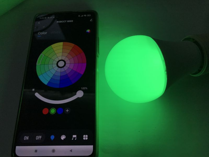 Controlling RGB/CCT LED Bulb with Tuya App Smartphone with Tuya app and glowing green RGB/CCT LED bulb.