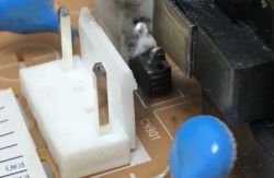 Zbliżenie na osmolony element elektroniczny oznaczony jako CN901 na płytce PCB.