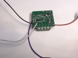 ATLO-SW1-TUYA Relay Module PCB with Programming Wires Green PCB of ATLO-SW1-TUYA relay module with black, white, red, and purple wires soldered to it.