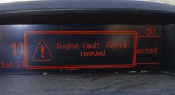 Zbliżenie na ekran samochodowy z komunikatem o błędzie silnika: Engine fault: Repair needed.