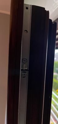 Zbliżenie na mechanizm okuciowy przy krawędzi skrzydła okna z dwoma śrubami.
