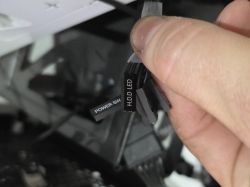 Zbliżenie na rękę trzymającą kable panelu przedniego: POWER SW i HDD LED