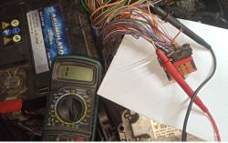 Multimetr mierzący napięcie na przewodach czujnika przy samochodowej kostce sterownika.