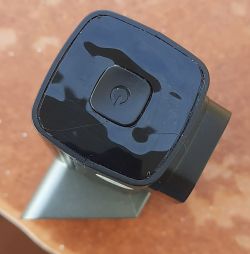 Zbliżenie na czarny przycisk zasilania na urządzeniu elektronicznym z widocznymi pęknięciami na powierzchni.