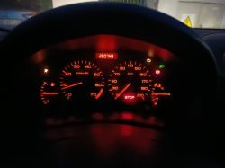 Wskaźniki na desce rozdzielczej samochodu, w tym prędkościomierz i sygnalizacja stop.