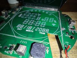 Close-up of a green printed circuit board with a digital display and electronic components.