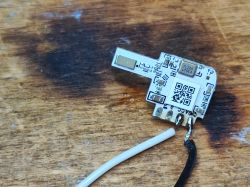 QS-WIFI-ECC02 Module on Wooden Surface The image shows a QS-WIFI-ECC02 electronic module with wires on a wooden background.
