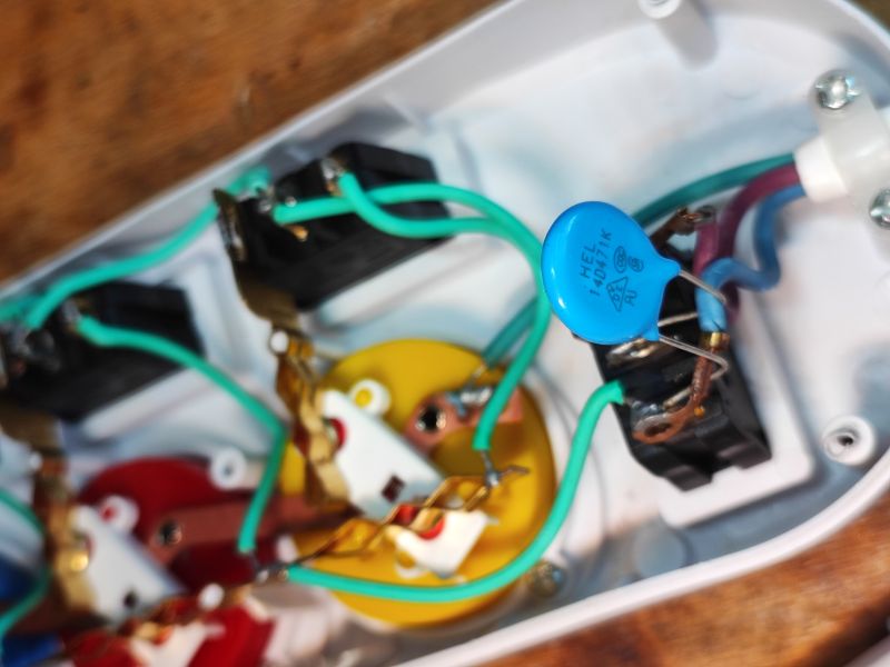 Interior of Power Strip with Varistor Interior of a power strip with colorful sockets, visible green wire and blue varistor.