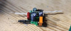 Electronic Module with Wires and Capacitors Electronic module on a wooden surface with visible capacitors and wires.