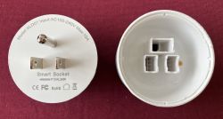 Disassembled smart socket: plug with printed specs and empty white housing on a red background