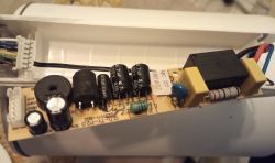 Circuit board in a white housing with capacitors, resistor, black rectangular component, and wire connectors