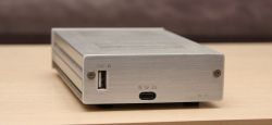 Metal enclosure of a headphone amplifier with visible USB ports and labels.