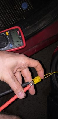 Osoba trzymająca miernik i wtyczkę z przewodami w samochodzie