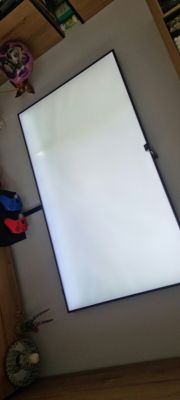Ekran telewizora QLED z widocznymi jasnymi plamami na białym tle