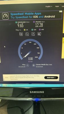 Ekran testu prędkości internetu na monitorze komputera z wynikami: pobieranie 9,65 Mbps, wysyłanie 12,28 Mbps, ping 49 ms, operator Plus.