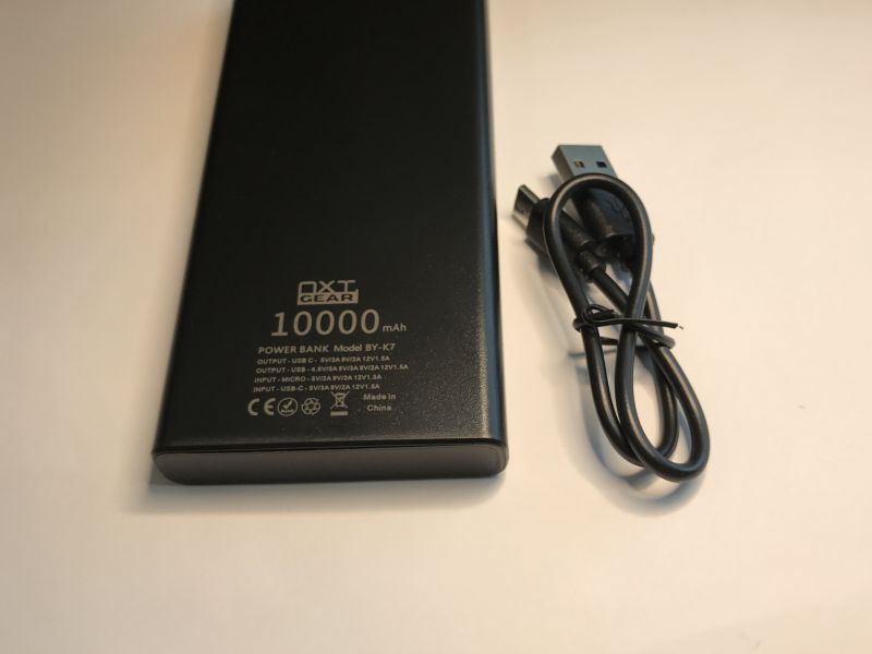 Black NXT Gear BY-K7 10000 mAh power bank with USB cable next to it