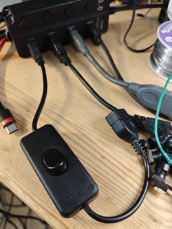 USB hub with multiple connected cables and a rotary switch on a wooden desk