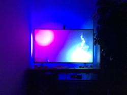 Backlit TV with dynamic LED lighting in blue and purple tones in a dark room