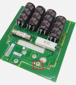 Płytka PCB z kondensatorami, bezpiecznikiem i zaznaczonym uszkodzeniem ścieżki