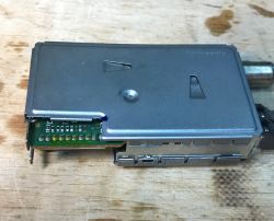 Moduł elektroniczny z pokrywą metalową i widocznymi złączami.