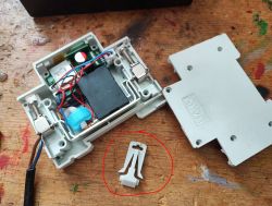 Open relay with visible electrical components and a plastic clip nearby.