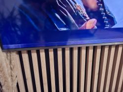 Pasek zniekształceń na dole ekranu telewizora TCL wiszącego nad drewnianą szafką