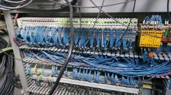 Panel sterowania z niebieskimi przewodami i modułem bezpieczeństwa w maszynie CNC.