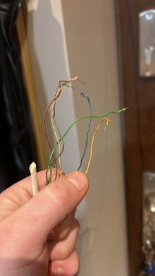 Zbliżenie na rękę trzymającą kilka kolorowych przewodów elektrycznych: zielony, czerwony, niebieski, żółty i brązowy.