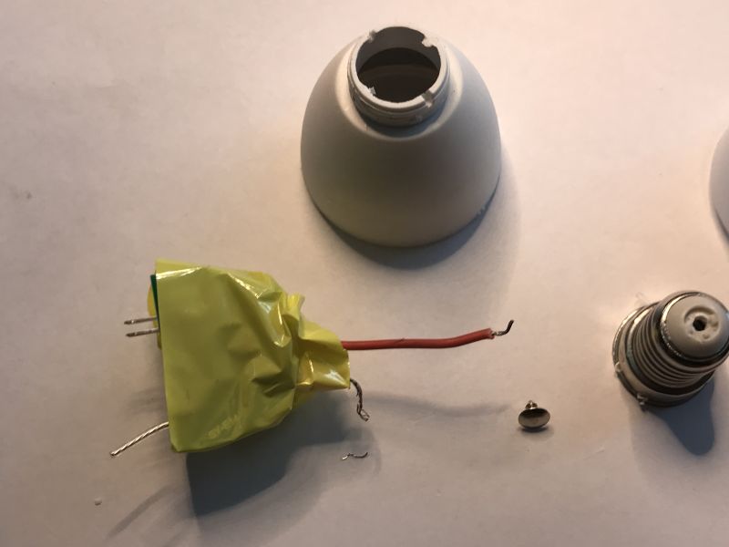 Tuya LED Smart Bulb Disassembled Disassembled Tuya LED smart bulb with dome, wires, socket, and taped circuit component laid out.