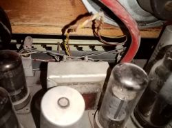 Wnętrze starego urządzenia elektronicznego z widocznymi lampami próżniowymi i przewodami.