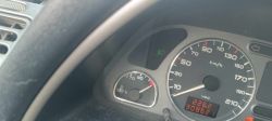 Zbliżenie na deskę rozdzielczą samochodu z widocznym wskaźnikiem temperatury silnika i prędkościomierzem.