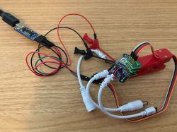 Programming CB3S LED Controller with Probe Clips Programming a LED controller using probe clips and wires on a wooden surface.